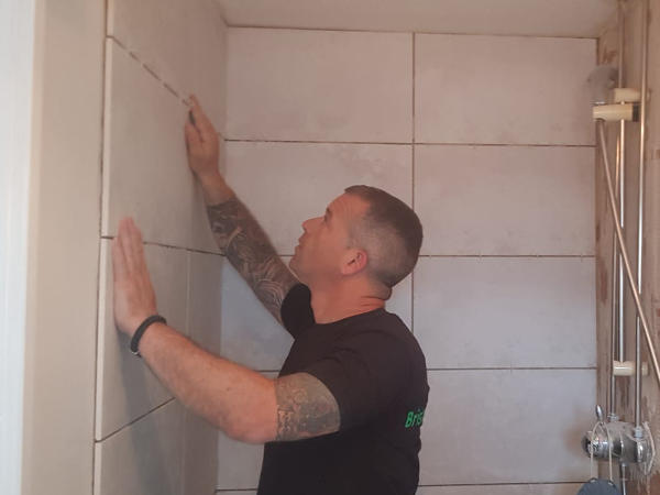 Person laying bathroom tile on a wall