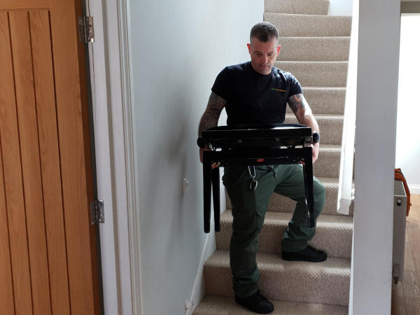 Man removing a piano stool from a property