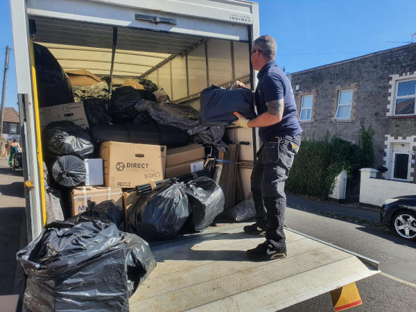 Person loading black bags of items on to a van