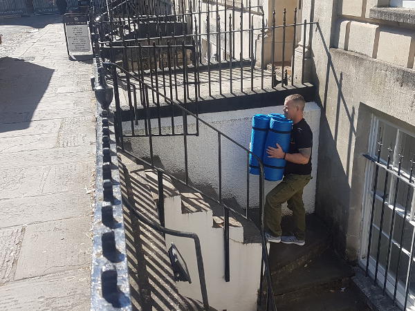 Operative walking up stairs carrying items for recycling